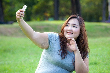 美丽电话户外漂亮的胖女人在公园玩旅行自拍绿色高清图片素材