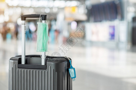 机场行李箱上的消毒酒精和口罩背景图片