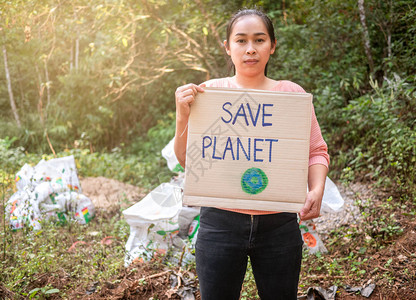 行进温暖的拿着拯救地球海报的年轻女子展示了抗议森林塑料污染的标志世界环境日零废物的概念节省图片
