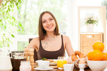 桌子熏肉微笑的年轻女人在家吃早餐的肖像美丽图片