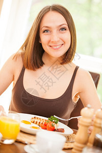 快乐的屋在室内微笑年轻女人在家吃早餐的肖像图片
