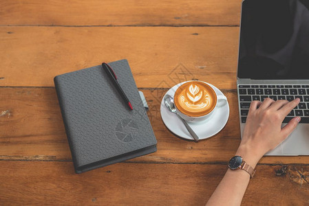 电子商务主题妇女使用笔记本电脑和咖啡杯笔记本电脑以及和咖啡杯人与饮酒和技术概念杯子图片