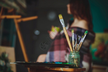一名女艺术家背景下的调色板上油涂料和漆刷子画的缝合木头省创造图片