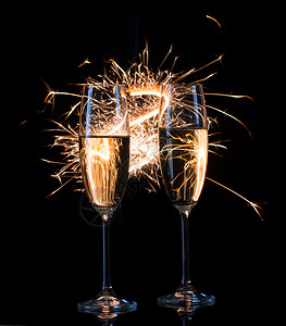 快乐的焰火庆祝婚礼和新年回旋空间的概念两杯香槟在孟加拉光的摇晃中喝着两杯香槟两杯香槟在孟加拉光的摇摆中喝着双杯香槟黑背景红酒杯图片