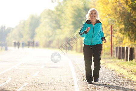 追踪70岁的老年妇女在明秋晚的Pedestrian漫步道上慢跑蓝色的户外图片