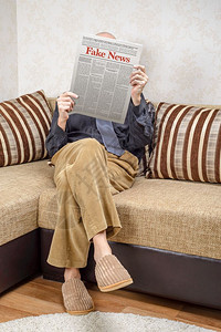房间衬衫一名戴眼镜的男人坐在家里沙发上看报纸导假新闻冒消息LoremImpsum文本大报图片