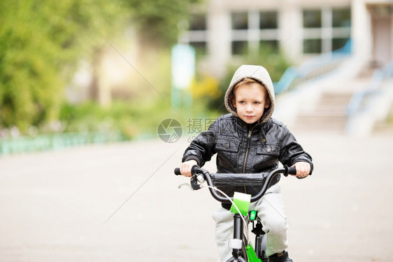 舵手穿着黑色皮夹克的可爱小城市男孩肖像风格孩子这男学会骑自行车孩子驾驶自行车孩子驾驶脚踏车脸城市的图片