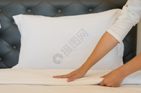 白种人家政年轻的旅馆女青在干净的房间里准备床上有干净白毯子卧室有枕头和床单早上睡衣用软毛巾新鲜的图片