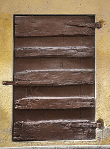 陈年木板弃具有石墙壁黄色背景的压实棕木制窗百叶图片