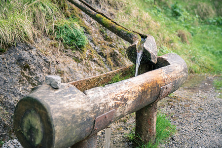 来源绿色高山意大利Bergamo附近ValVertova种子的木制喷泉源流出未过滤的天然原始水图片