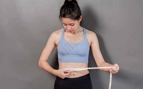 测量身高完美的皮肤亚洲健康美丽和运动的女肖像在锻炼和饮食后用胶带测量腰部运动员背景