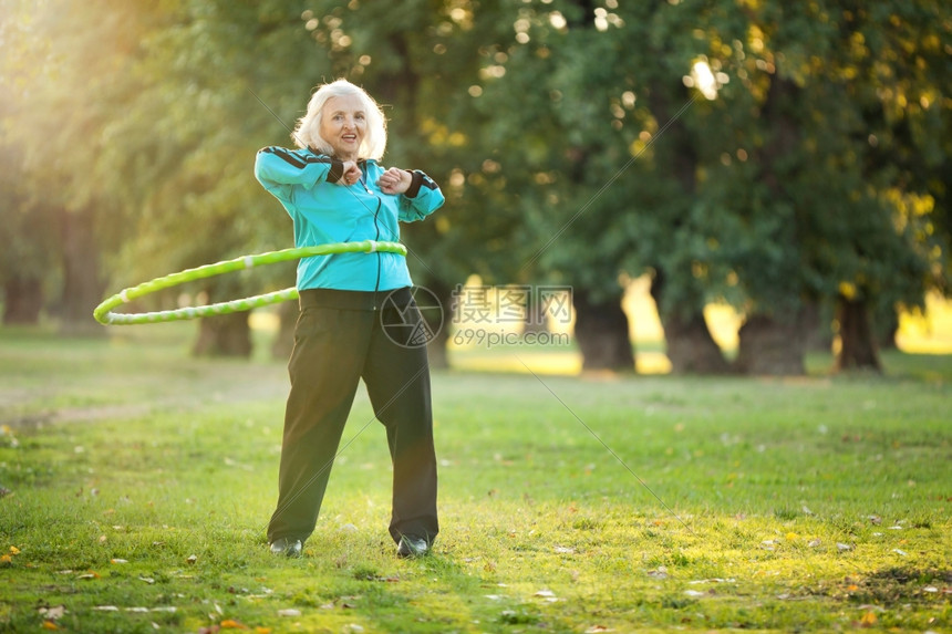 高级的诺维科夫卫生保健70岁的老年妇女在明日秋夜绿草地上与塑料小屋一起锻炼活动并在绿色草地举行图片