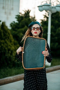 复古的身着老黑色波尔卡圆点装饰的年轻女子手持复式提箱在外面摆放感的女孩图片
