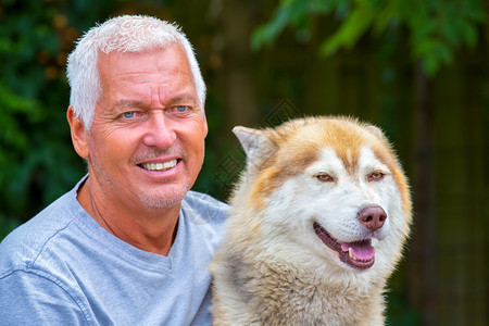 自豪的雪橇犬带成年哈斯基狗的欧洲男子肖像狼疮图片