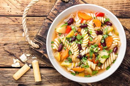 桌子素食主义者可口蔬菜汤配有新鲜番茄大菜胡萝卜锌洋葱辣椒豆子和意大利面食图片