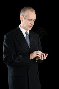 黑色的西装高级商人在手机上用黑色背景写短号或拨以黑人背景英俊的夹克图片