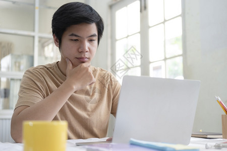 商人现代的使用笔记本电脑在家庭办公室工作的青年男子利用在线连技术促进商业教育和通讯工作在网上连接技术促进商业教育和通讯智力图片