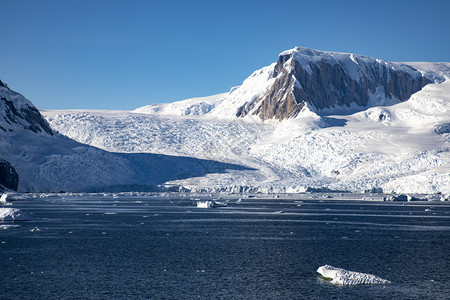 冰雪和覆盖的山脉之间冰川舌头流向南极海地点取消水图片