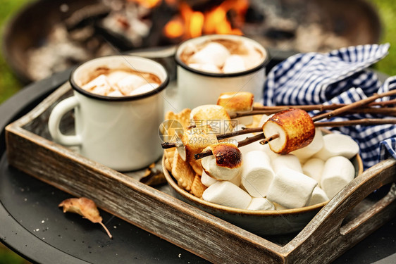 舒适派对两杯咖啡可或热巧克力和烤棉花糖的切片在营火期间使用秋季节假日户外招待篝火图片