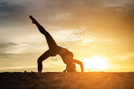 健康女在日落时沙滩上做瑜伽图片
