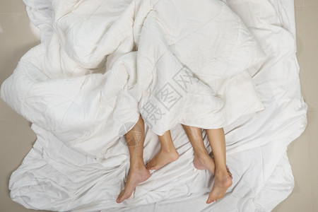 松弛在卧室床单下的上男女双脚紧贴地亲近情人男图片