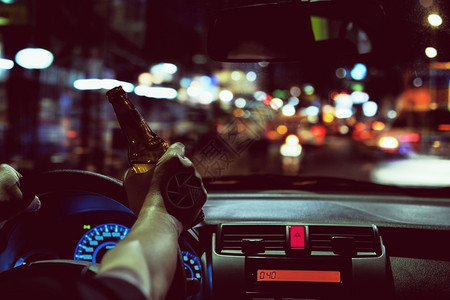 人晚上在城里开车时喝啤酒左手驾驶系统很危险左手驾驶系统温暖的夜晚违反图片