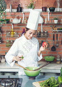 女厨师黑发白西装制服苹果和柠檬在厨房准备烹饪健康食品菜盘上的蔬绿碗行业人们家图片