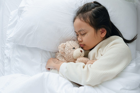 亚洲小女孩睡在卧室里抱着泰迪熊睡觉学前班美丽梦图片
