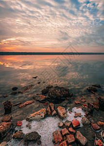 日落时盐湖的全景观仰望着夏日夕阳红光下湖面的石头黎明灾难木制的图片