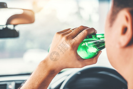 醉酒男子驾驶一辆汽车在路上载着啤酒瓶的车危险醉酒驾驶概念男注意力瓶子图片