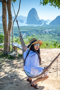 极端坐在泰国SamedNangChee的PhangNgaBay山顶上的年轻女子徒步旅行悬崖图片