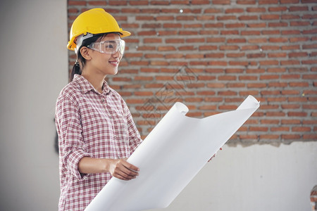 承包商格子项目女建筑工程师在地身戴安全白色钢帽的建筑工场薪女程师土木带有硬帽子安全头盔的女建筑工程师概念a妇女建筑工程师图片