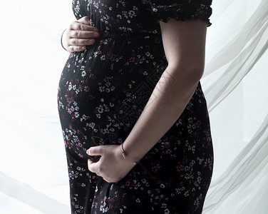 美丽的为人父母年轻白色灰背景的孕妇腹部拥抱着期待婴儿的概念图片