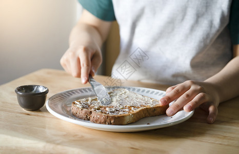 他的儿童在早餐时用黄油烤吐司Kid正在准备食物Heahtylifestyye概念孩子的手在面包上撒黄油孩子将用于烤面包男生活图片