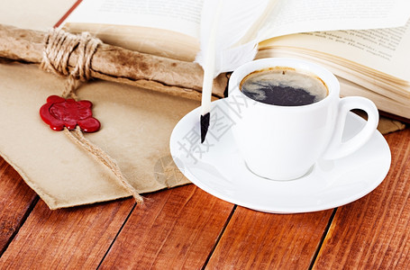 马克杯咖啡配有钢笔和纸卷一本木制背景的书碟子图片