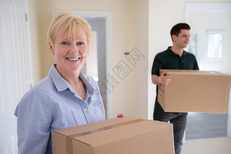 公寓激动在搬家日与运工帮助下高级妇女在退休后带箱进入新家时被降级的肖像水平图片