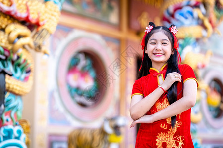 漂亮的旗袍孩子身着中华新年节国青春红传统香藏装饰的可爱亚洲小女孩长得一脸美丽的笑并戴着彩礼图片