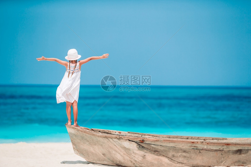 暑假在海滩上戴着草帽的可爱小女孩背影暑假在海滩上的可爱小女孩假期晴天松弛图片