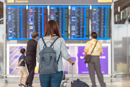 在现代机场旅行和运输概念的飞行信息屏幕上登入机检查时背着行李站在飞板上的亚洲女旅行者背面在飞信息屏幕上登机国际的游客木板图片