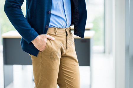 蓝色的或者专业一名商人Manrsquos手持棕色或金裤口袋身着蓝外套和衬衫在办公室背景中穿着蓝色夹克和衬衫在办公室背景中图片