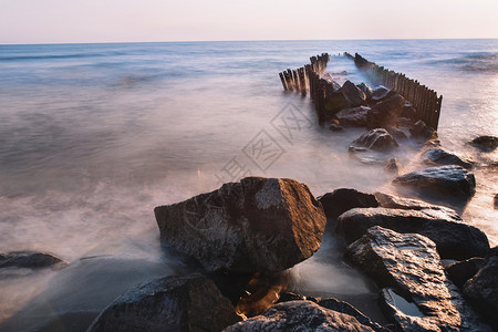 黎明黄昏夏季风景海边有粉红日落天空海滩上还有石头在海面建造最微小的风格接触图片