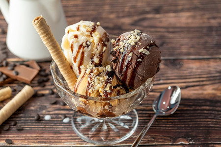 服务杯子盘巧克力奶油和焦糖罗马人冰淇淋在玻璃碗里加了栗子和巧克力酱图片