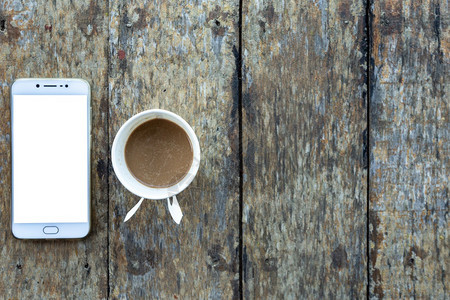 老的平坦空白智能手机和咖啡杯纸印在顶视图的旧木板桌上图片