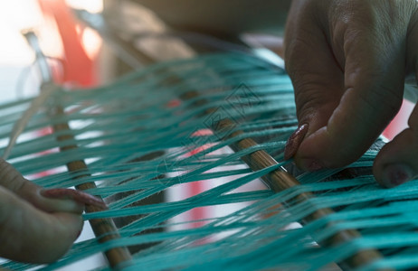 在织机上工作的妇女用于编织手工物纺编使用传统手工织布机在棉线上编织泰国亚洲文化中的纺织或布料生产传统的女士工厂图片