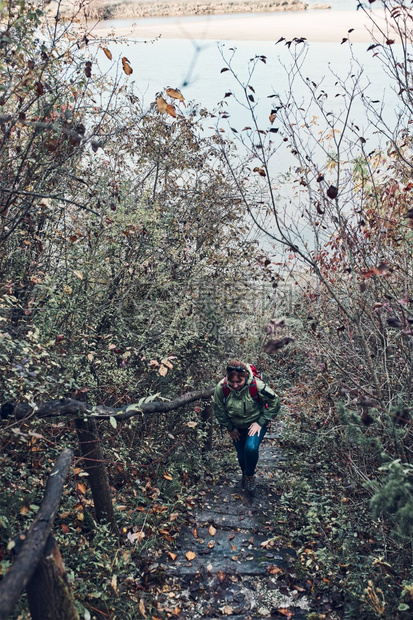 积极地森林户外女在秋季旅行途中上楼出活跃的中年妇女带着背负包积极度过秋季冬玩天女人在旅行时上楼去图片