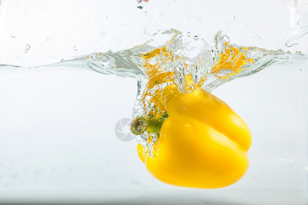 食物干净的艺术甜辣椒在水中喷洒黄色的白背景甜辣椒是一种不图片