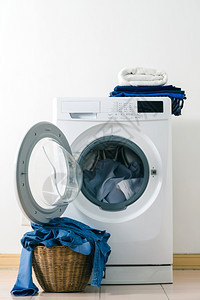 洗钱鼓将衣机和服装在篮子中的白色背景洗涤机和衣物国内的图片