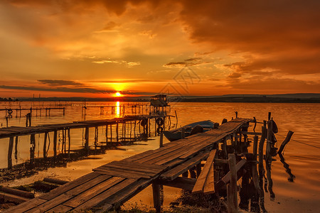 日落在海岸用木头码闪亮假期红色的湖图片