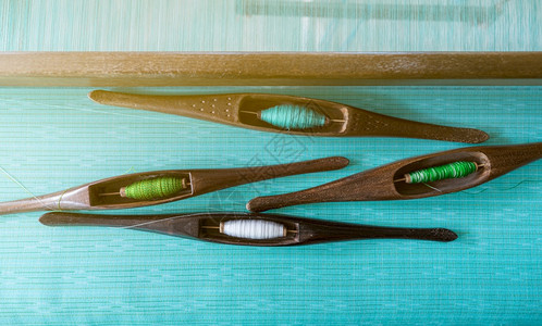 织机上梭工具中纱线的顶视图纺织物编使用传统布机和梭进行编织泰国纺或布料生产绿色手工布服装业的细绳图片
