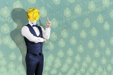 一个穿西装的男人着一个灯泡由折叠黄纸代替头顶用举起的手指概念在灯泡背景上象征想像力创新图片